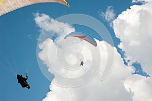 Two paragliders flying in the blue sky.