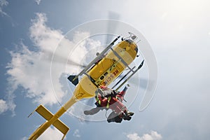 Two paramedics hanging on rope under flying helicopter