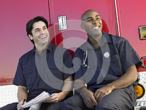 Two paramedics sitting by their ambulance