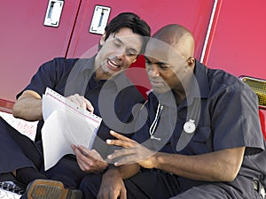 Two paramedics sitting by their ambulance