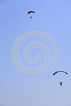 Two paratroopers descend against a blue sky