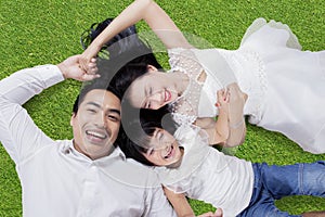 Two parents and child lying on grass