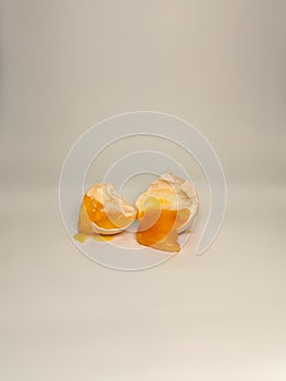 two parts of the broken chicken eggs emit the inner contents with a white background