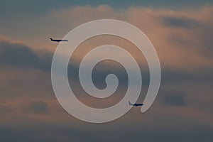 Two passenger jets passing by through cloudy skies