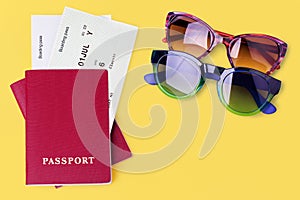 Two passports, flight boarding passes, tickets, sunglasses yellow background close up top view, airplane travel concept, holidays