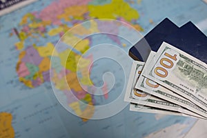 Two passports and one hundred dollar bills. Against the background of a world map. Silhouettes of continents are visible