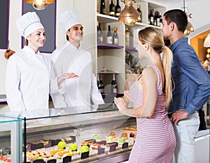 Two pastry chefs warmly greeting couple