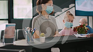 Two patients with face mask talking to facility receptionist