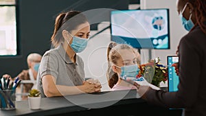 Two patients with face mask talking to facility receptionist