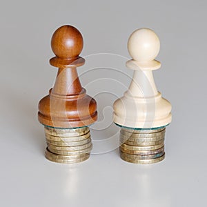 Two pawns chess pieces on columns of coins, symbolizing the equality of income