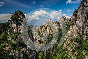 Two peaks on each side with some steep sharp peaks in the middle and blue sky and small clouds on the horizon in Huang Shan China