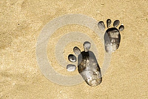 Two pebble footprints on the surface of the desert sea sand. Games on the sand and on the beach. A copy of the space