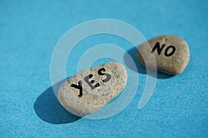 Two pebbles with the text yes and no on a blue table