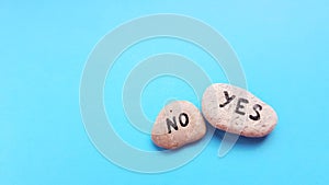 Two pebbles with yes and no text on blue table