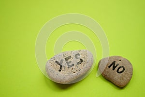 Two pebbles with yes and no text on them. Green table