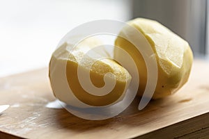 Two Peeled Potatoes on Wooden Board CloseUp