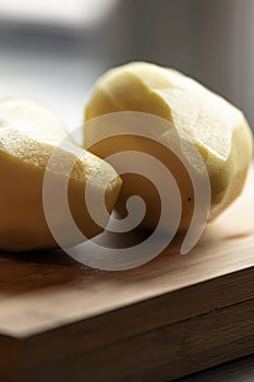 Two Peeled Potatoes on Wooden Board CloseUp