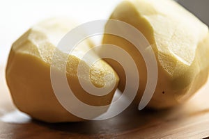 Two Peeled Potatoes on Wooden Board CloseUp