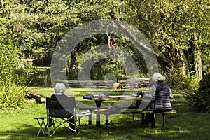 Two Pensioners With Grey Curly Hair Sitting In The Shade