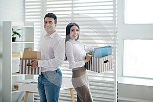 Two peoole holding boxes with office stuff and smiling