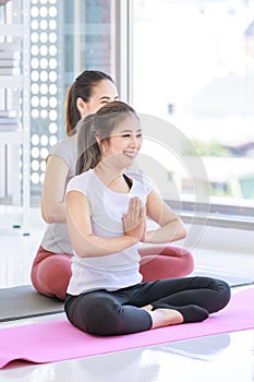 Two people Asian beautiful healthy fit slim female sporty athlete model in sport bra and leggings sitting crossed legs in lotus