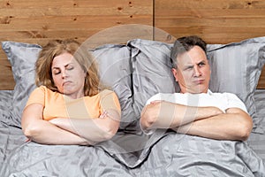 Two people in bed, a man and a woman lie dissatisfied with each other. Relationship concept