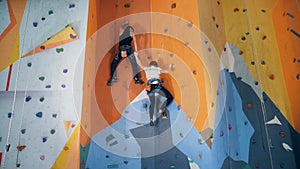 Two people are climbing an artificial training wall