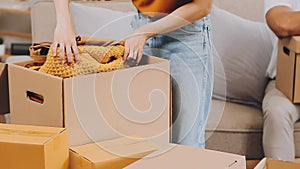 .Two people couple interracial family ameste in living room in new apartment open cardboard boxes receive parcels with orders from