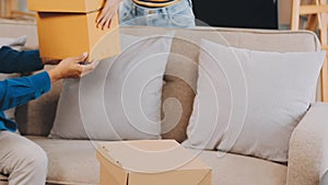 .Two people couple interracial family ameste in living room in new apartment open cardboard boxes receive parcels with orders from