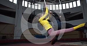 Two people doing aerial gymnastics on a hoop, hanging and doing splits, 4k