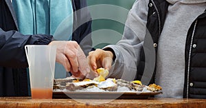 Two people eating oysters at a street food market.