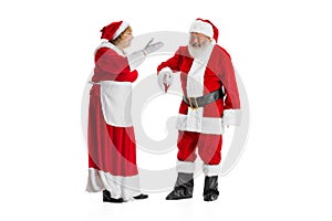 Two people, elder man and woman, Santa Claus and missis Claus in traditional New Year costume talking isolated on white