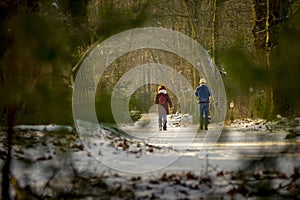 Two people enjoying an afternoon walk in the winter forest with snow