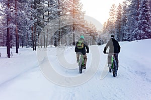 two people with fat bikes riding snowy winter forest trail