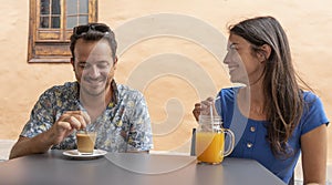 Two people flirting in a terrace having a date and smiling with relaxing atmosphere. Married Couple seated drinking a coffee and