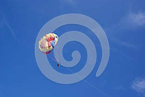 Two people glide with a parachute against the blue sky. Selective focus