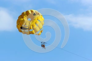 Two people are gliding using a parachute on the background of the blue sky. Summer background