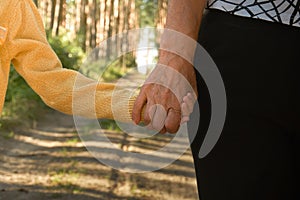 Two people hold hands, the older and younger generation of people, grandmother and granddaughter holding hands. Walk in