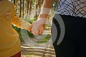 Two people hold hands, the older and younger generation of people, grandmother and granddaughter holding hands. Walk in the park