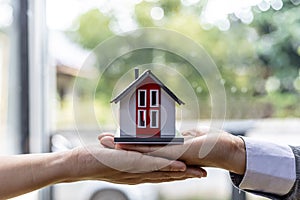 Two people holding a miniature house model, photo of home insurance concept, when buying a new home should have home insurance to