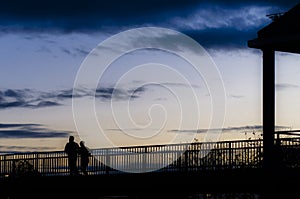 Two people jogging on bridge in silhouette