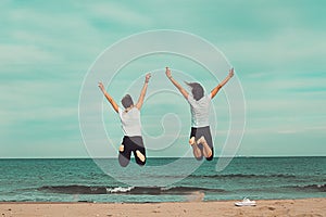 Two people jumping by the sea. Concept of fun on the beach.