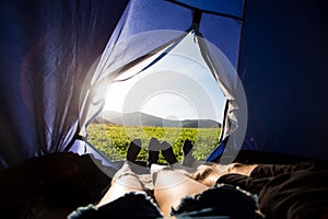 Two people lying in tent, view from inside. Couple camping with beautiful view of mountains