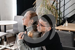 Two people, man and woman in cafe hugging, laughing and enjoying the time spending with each other. Couple in love on a
