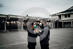 Two people in masks holding hands.Couple being divided by incurable infectious disease.Infection control,isolation.Loved one