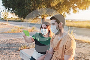 Two people mother and son in law in a mask and talking by video call with a smart phone outdoors. Social distancing against