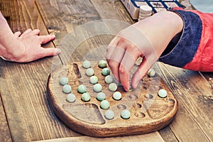 Two people play an ancient board game Mill. Reconstruction of entertainment and leisure in the old days. Vintage intellectual game