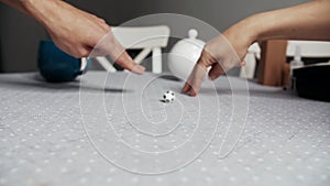 Two people play soccer with fingers using a small toy ball on the kitchen table.