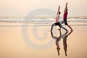 Two people practicing yoga in the sunset light on goa india beach. female and male acro yogi tantra flying copyspce