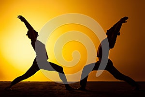 Two people practicing yoga in the sunset light